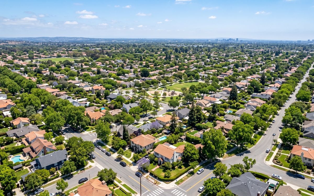 Vista aérea de um bairro residencial com ruas arborizadas e casas de telhado claro